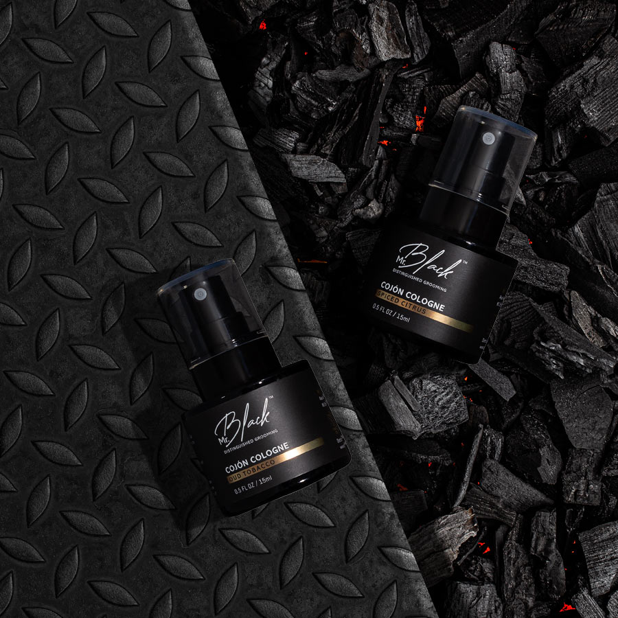 Two Bottles Of Cojon Cologne On Charcoal Background