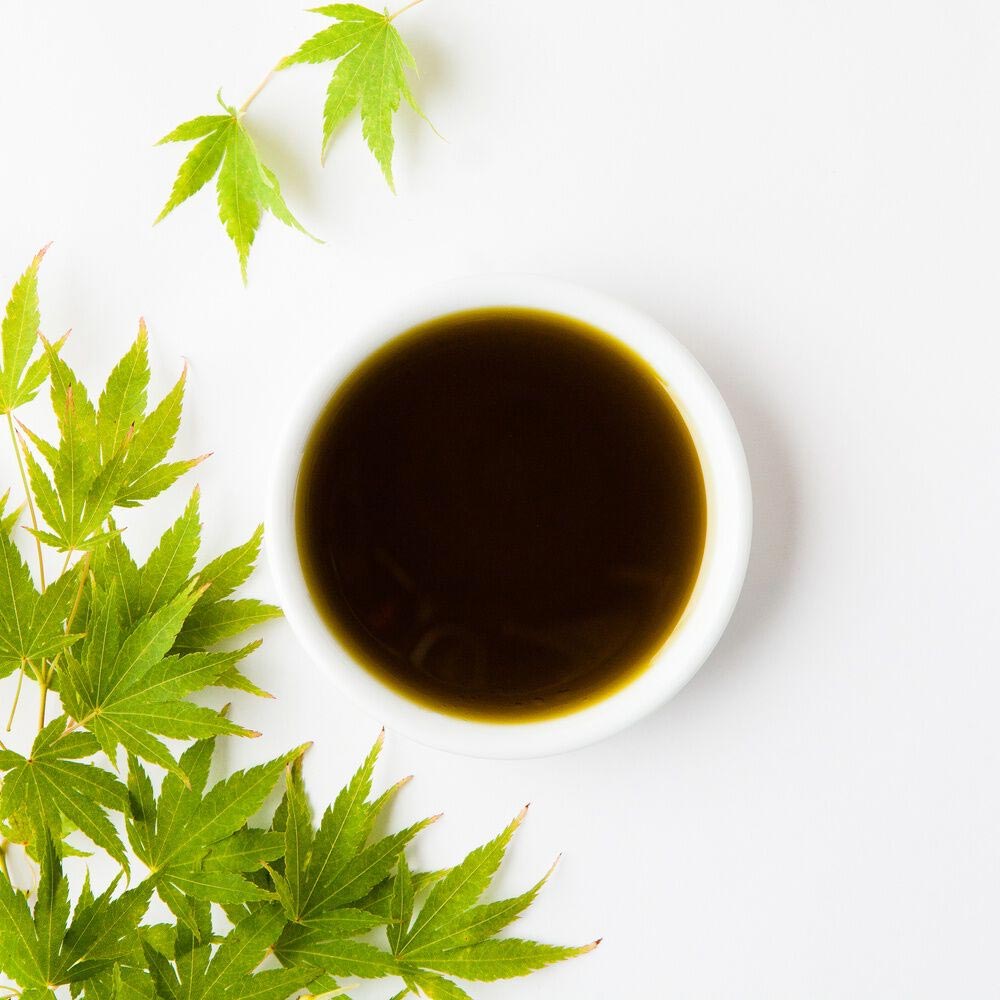 A Bowl Of Hemp Seed Oil with Hemp Leaves Around